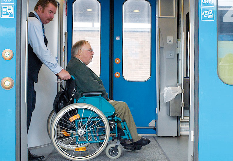 Ein Kundenbetreuer schiebt einen Rollstuhlfahrer durch einen Zug der WestfalenBahn.